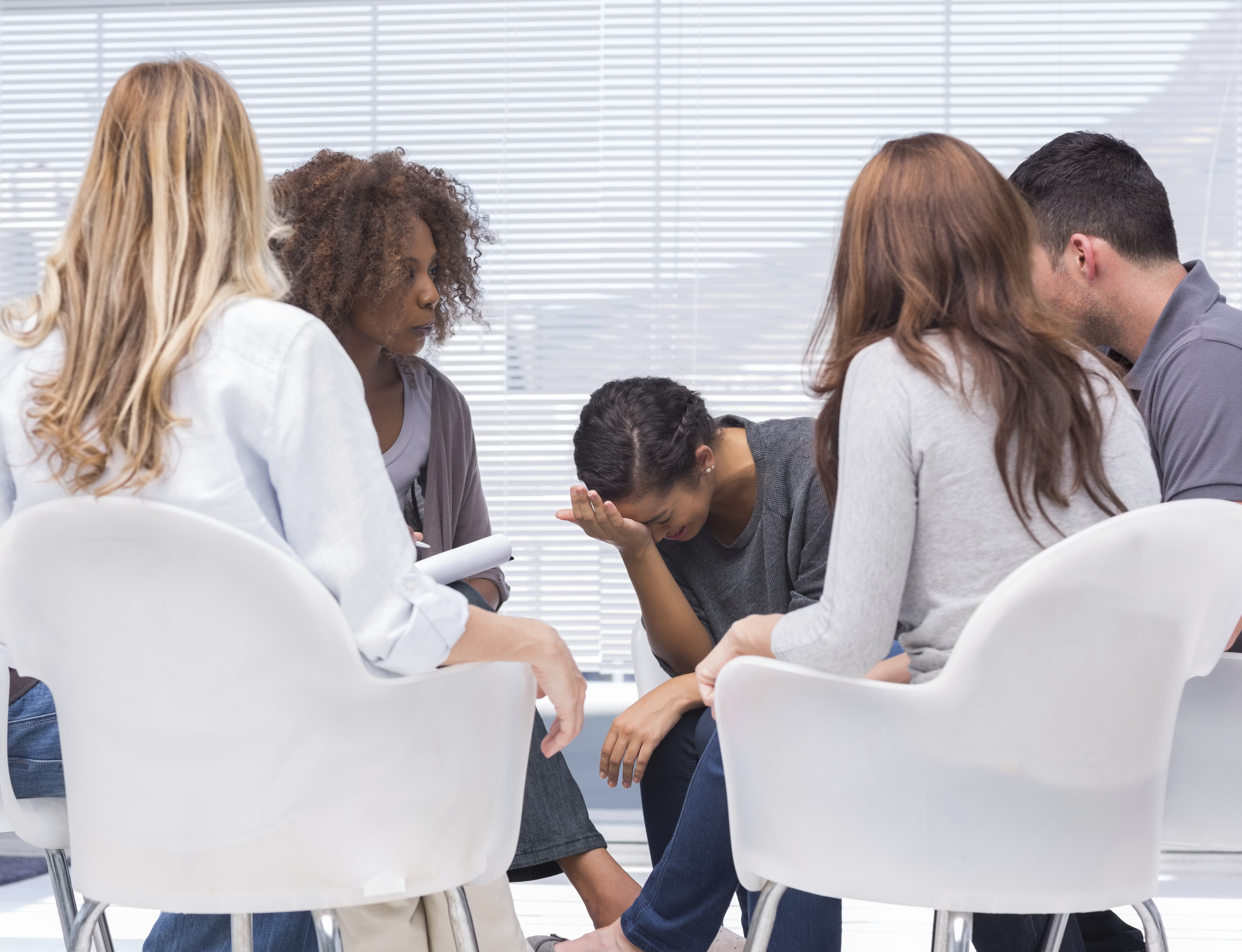 Psychologist taking notes while woman crying at group therapy